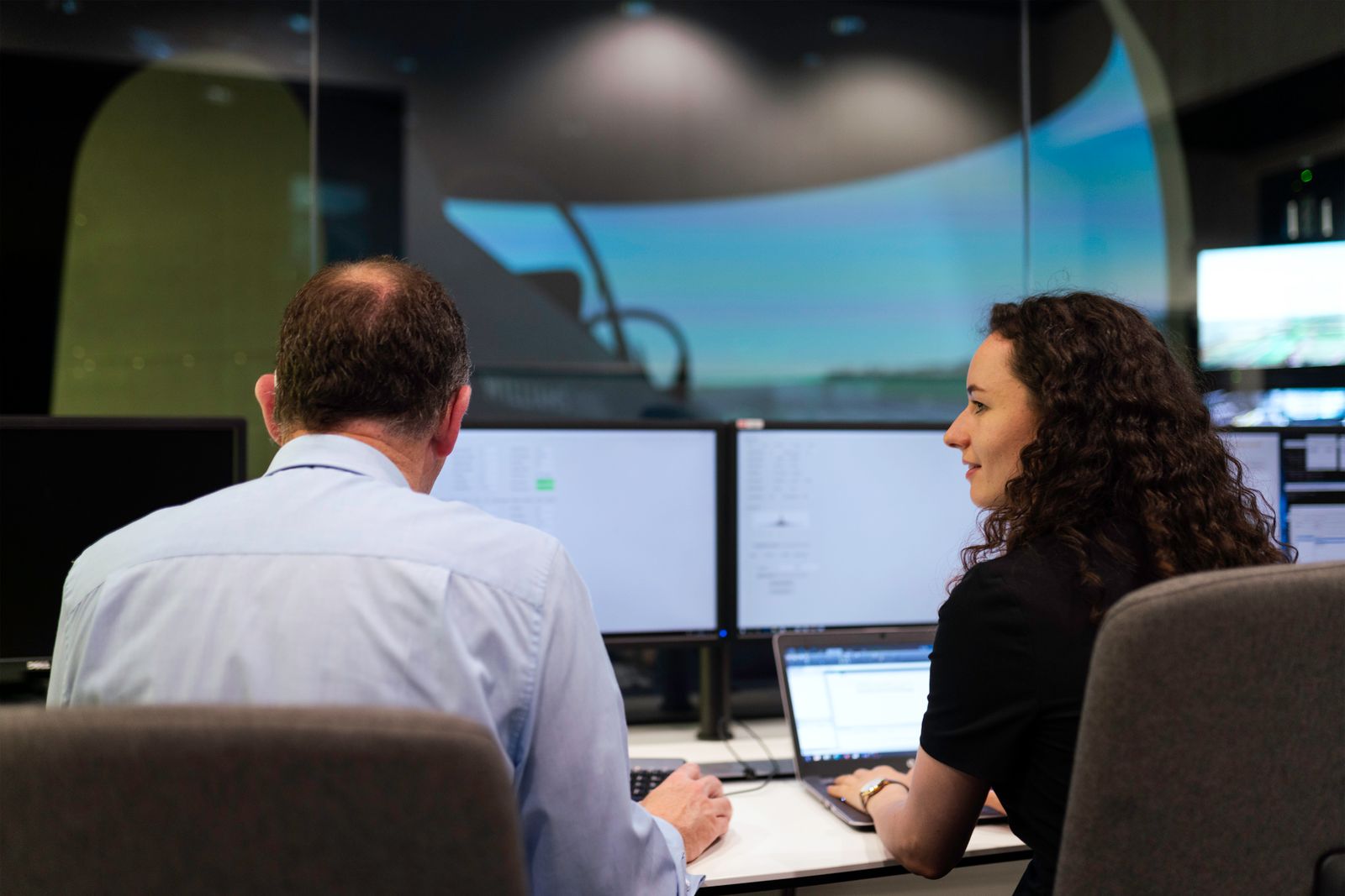 Engineers monitoring systems on multiple screens in a control room